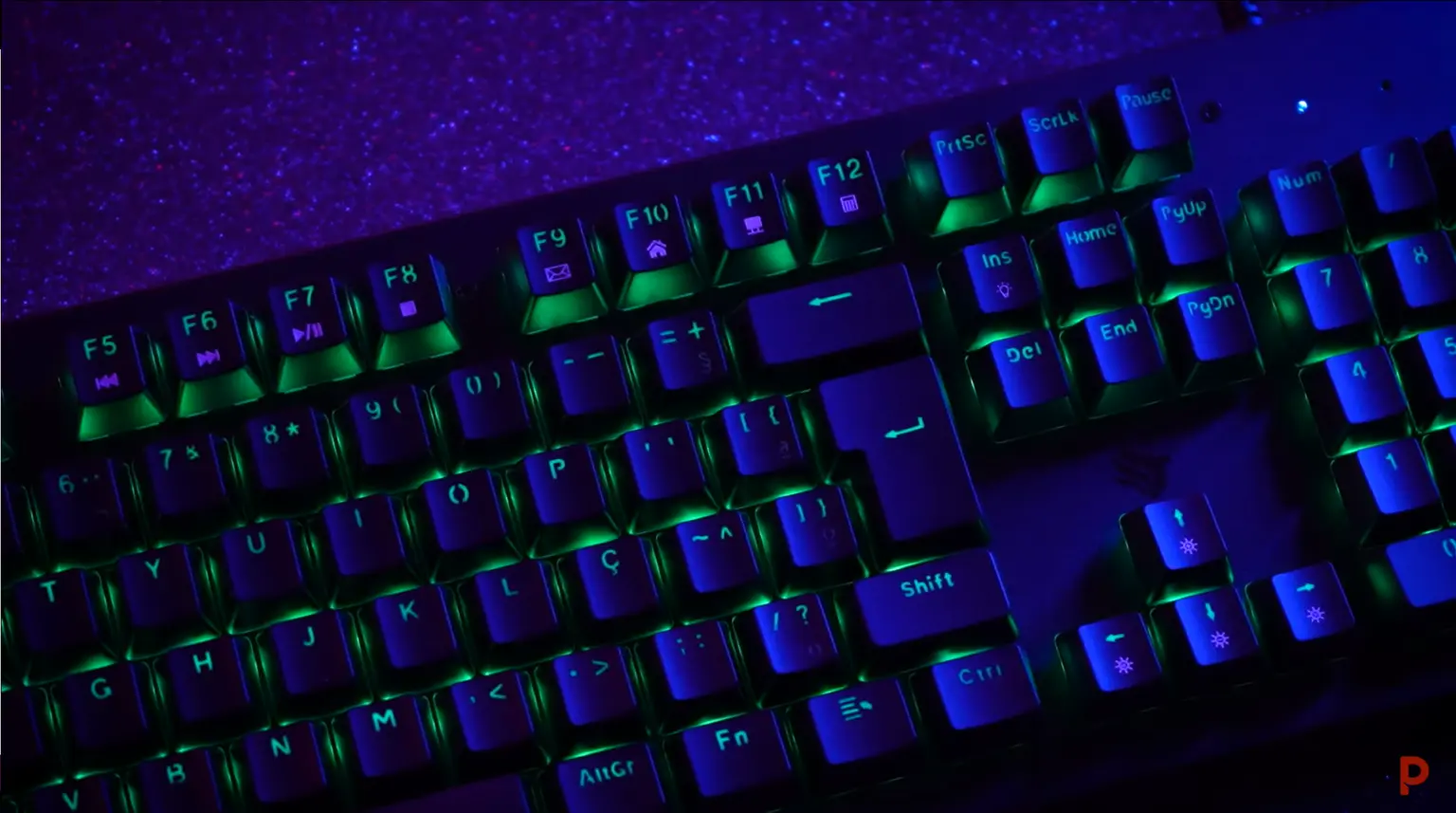 Teclado magnético gamer com iluminação RGB e teclas destacadas em azul e verde.